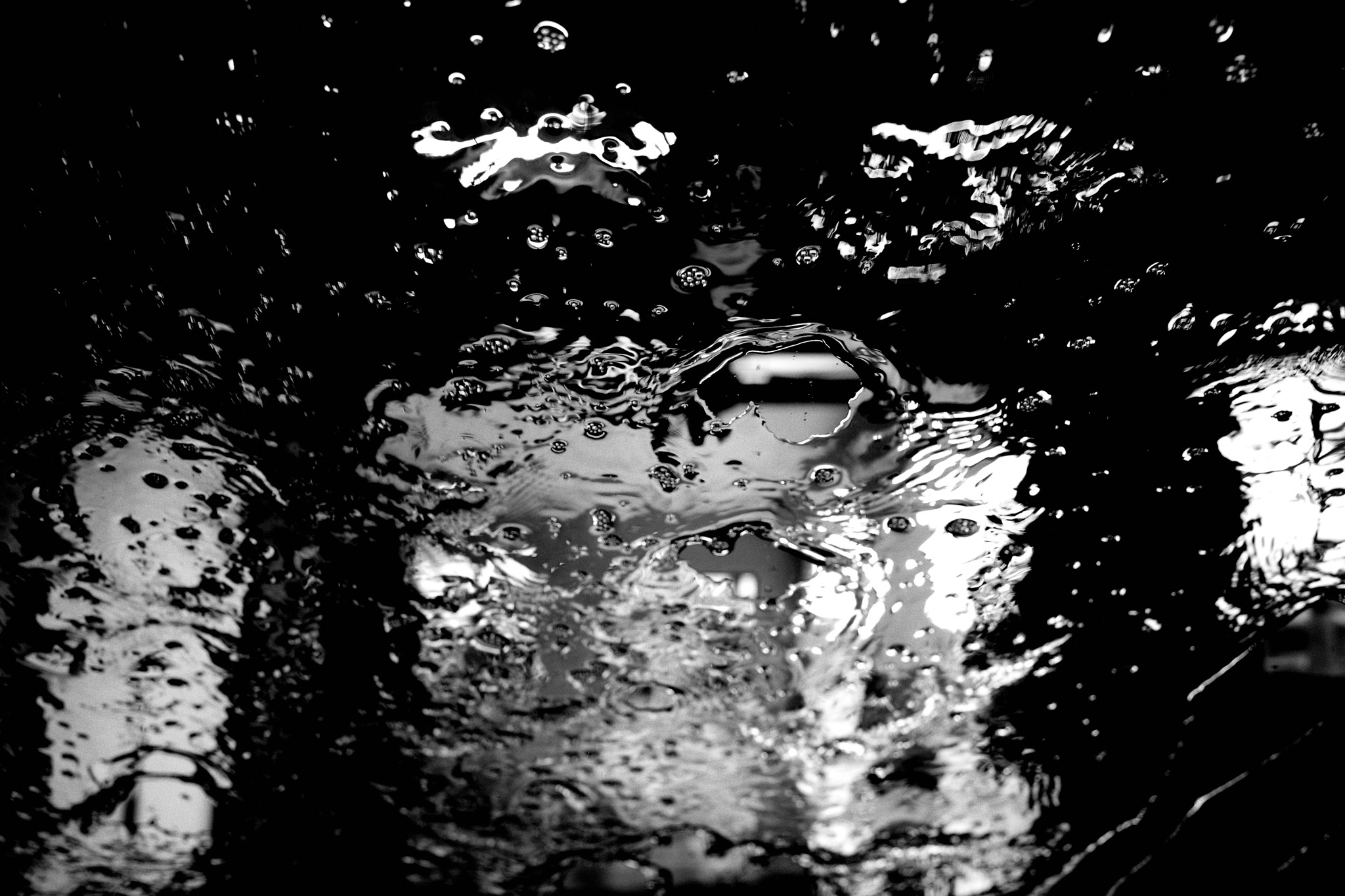 Black and white image of water on windshield at car wash.