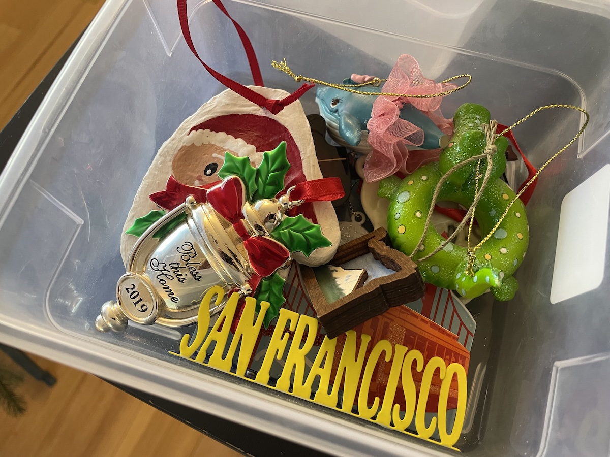 A small pile of personal Christmas ornaments, including travel keepsakes and a house blessing