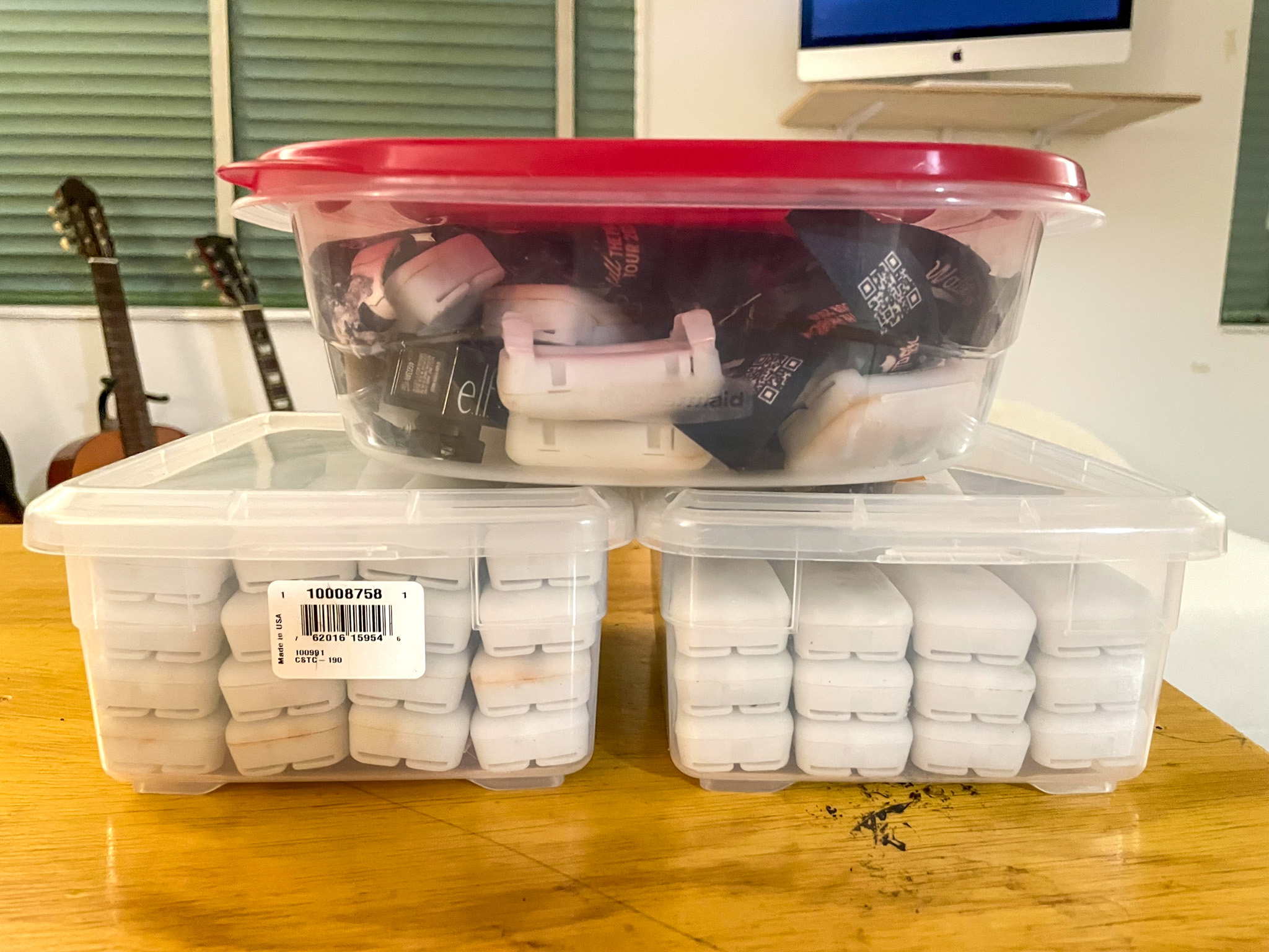 Three storage containers holding 93 PixMob wristbands stacked on a living room table.