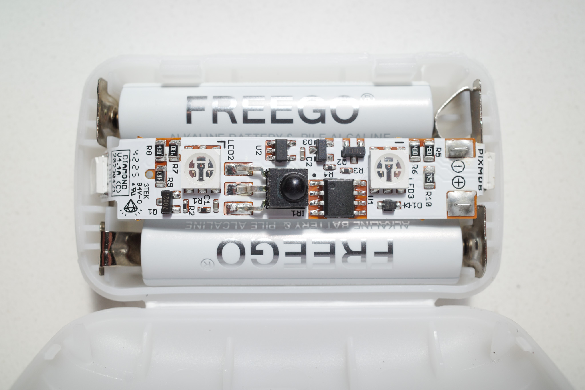 Interior of a PixMob X4 Gen3.1 wristband showing its circuit board, infrared receiver, LEDs, and two batteries.